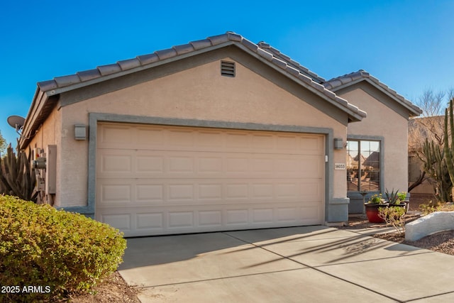 view of front facade with a garage, driveway, a tile roof, and stucco siding