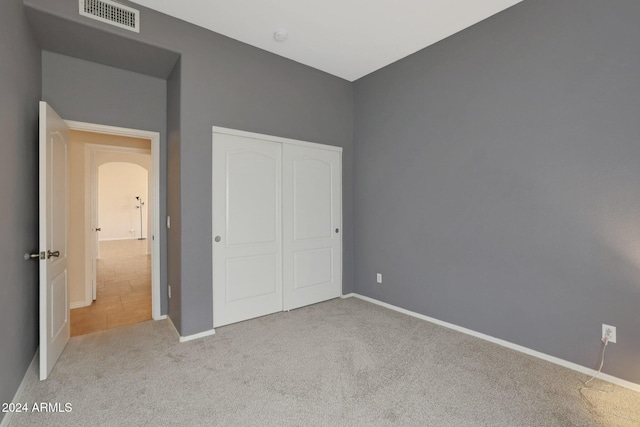 unfurnished bedroom featuring light colored carpet and a closet