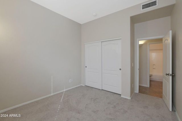 unfurnished bedroom with light carpet and a closet