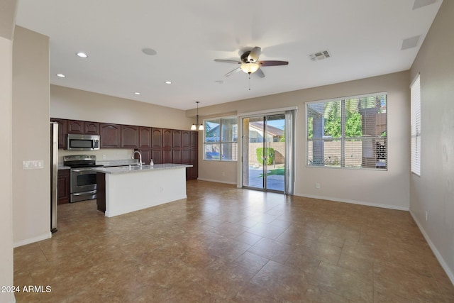 kitchen with pendant lighting, ceiling fan, an island with sink, appliances with stainless steel finishes, and dark brown cabinetry