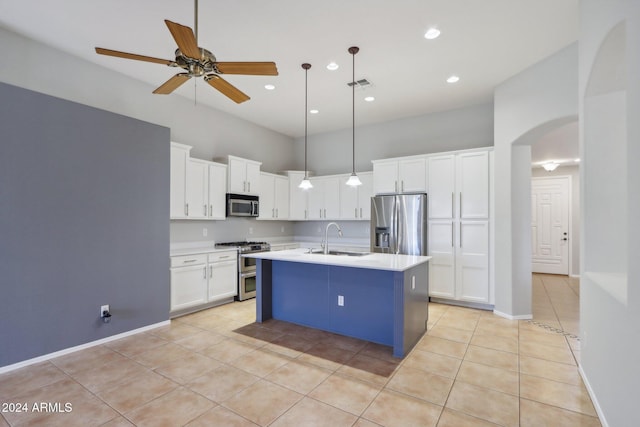 kitchen featuring a center island with sink, hanging light fixtures, ceiling fan, white cabinetry, and stainless steel appliances