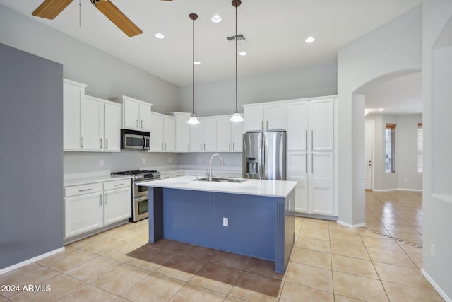 kitchen featuring stainless steel appliances, sink, white cabinetry, hanging light fixtures, and an island with sink