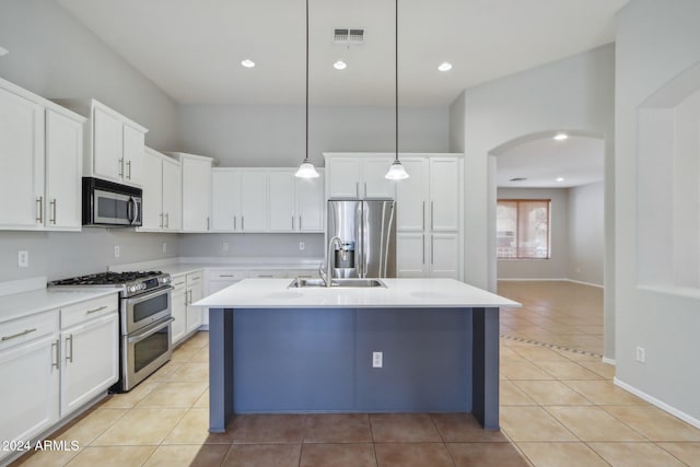 kitchen featuring a kitchen island with sink, white cabinets, decorative light fixtures, and appliances with stainless steel finishes