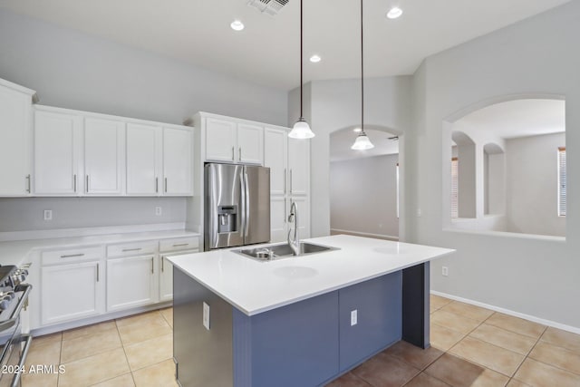 kitchen featuring appliances with stainless steel finishes, sink, decorative light fixtures, white cabinets, and an island with sink