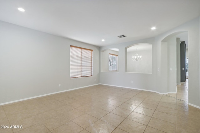 unfurnished room featuring a notable chandelier and light tile patterned floors