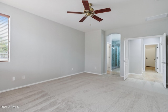 unfurnished bedroom featuring light carpet, connected bathroom, and ceiling fan