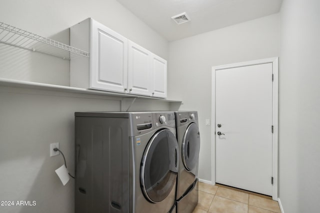 laundry area featuring cabinets, washing machine and dryer, and light tile patterned flooring