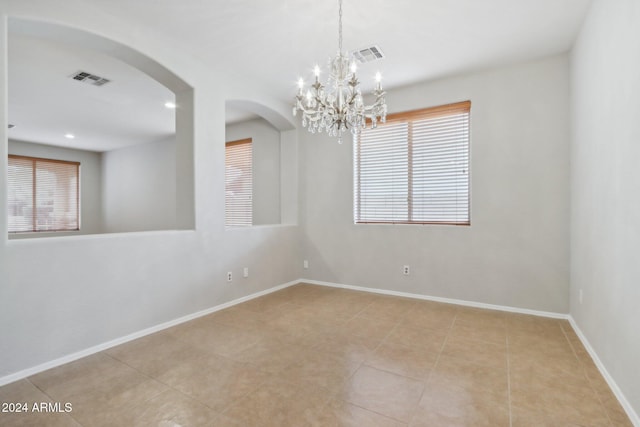 tiled empty room with an inviting chandelier