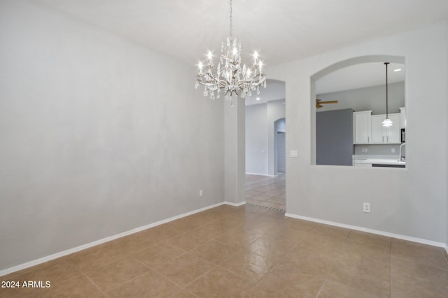 tiled empty room featuring ceiling fan with notable chandelier