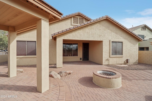 rear view of property with a patio and an outdoor fire pit