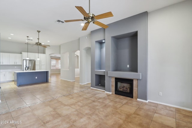 unfurnished living room featuring light tile patterned floors, ceiling fan, and a tiled fireplace