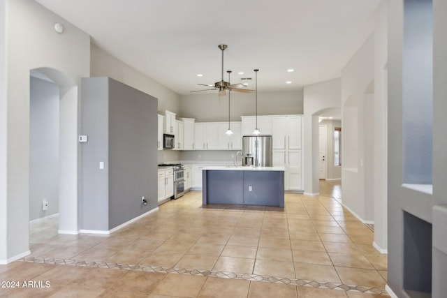 kitchen featuring appliances with stainless steel finishes, ceiling fan, light tile patterned floors, a center island with sink, and white cabinets