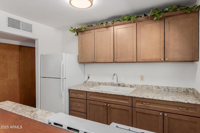 10012 N 16th Dr, Phoenix, AZ 85021 - kitchen featuring a sink, freestanding refrigerator, and brown cabinetry