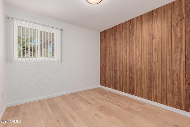10012 N 16th Dr, Phoenix, AZ 85021 - unfurnished room featuring light wood-style flooring, brick wall, wood walls, and baseboards