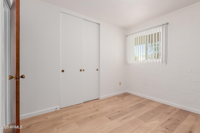 10012 N 16th Dr, Phoenix, AZ 85021 - unfurnished bedroom featuring light wood-style flooring, a closet, baseboards, and brick wall