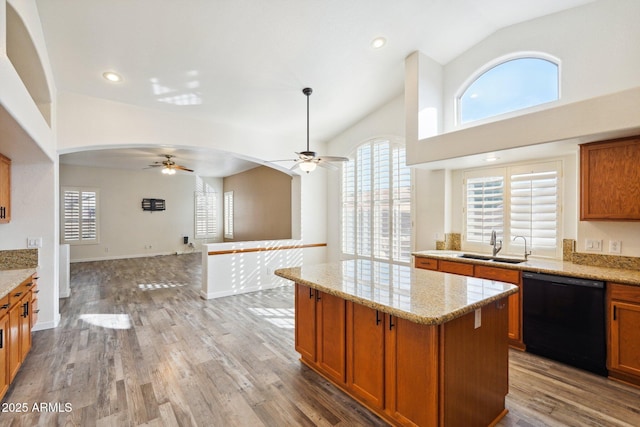 kitchen featuring sink, a center island, black dishwasher, light stone countertops, and hardwood / wood-style floors