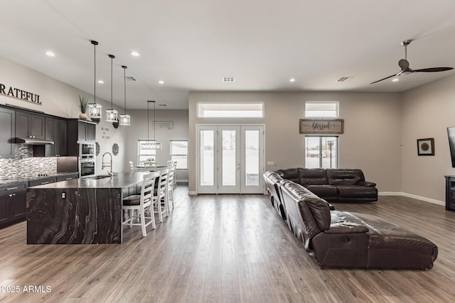 living room with ceiling fan, sink, a high ceiling, and hardwood / wood-style flooring