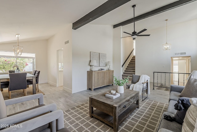 living room featuring a notable chandelier, wood finished floors, visible vents, stairway, and beamed ceiling