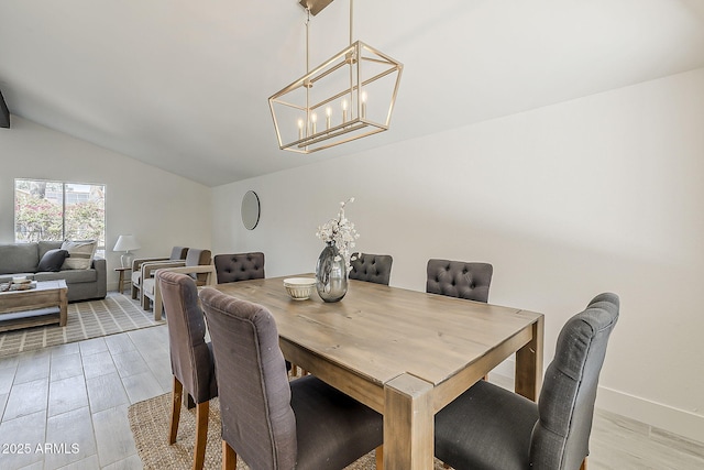 dining space with lofted ceiling, baseboards, and a chandelier