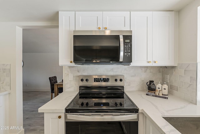 kitchen with light stone counters, appliances with stainless steel finishes, white cabinetry, and decorative backsplash