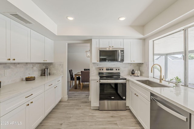 kitchen featuring stainless steel appliances, visible vents, a sink, and white cabinetry