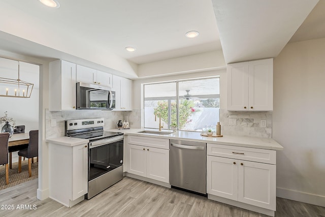 kitchen featuring appliances with stainless steel finishes, light countertops, white cabinets, and a sink