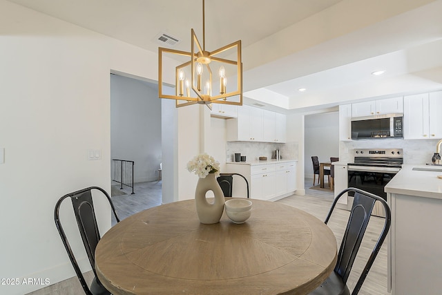 dining room with recessed lighting, visible vents, light wood finished floors, and an inviting chandelier