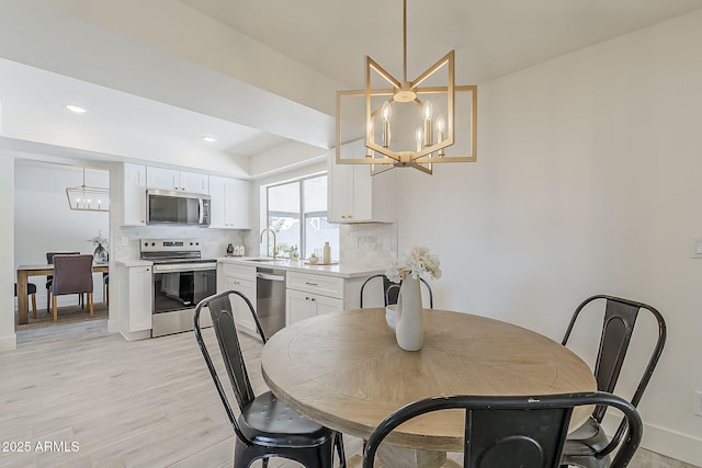 dining room featuring baseboards, light wood-style floors, recessed lighting, and a notable chandelier