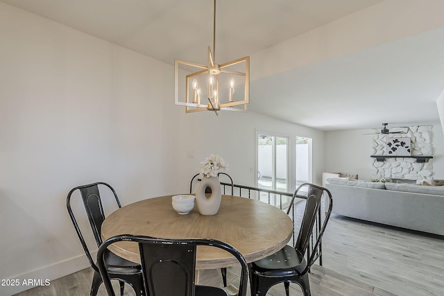 dining area with light wood-type flooring, baseboards, and a notable chandelier