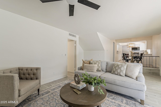 living area with light wood-type flooring, baseboards, visible vents, and a ceiling fan