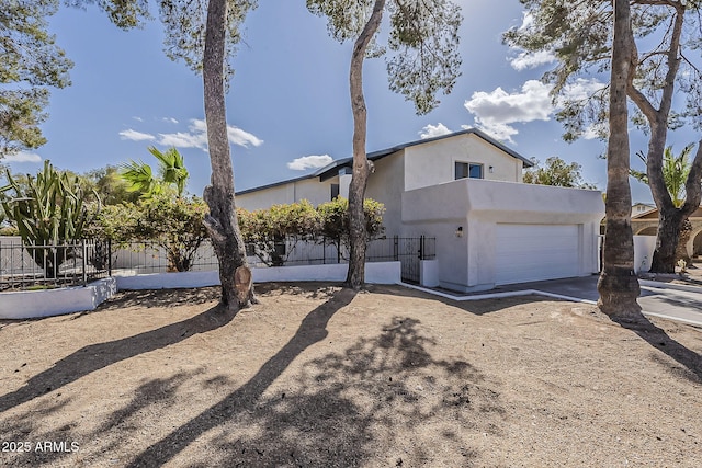 view of front of house with a garage, driveway, fence, and stucco siding