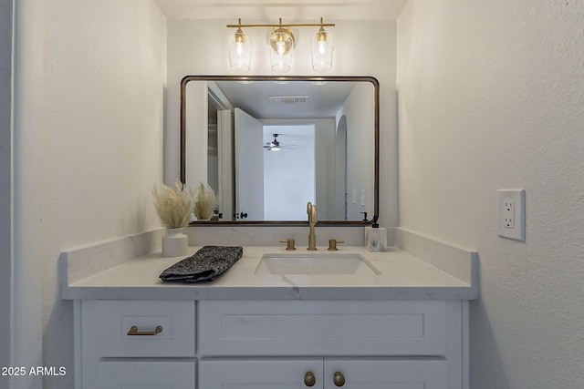 bathroom with visible vents, a textured wall, and vanity