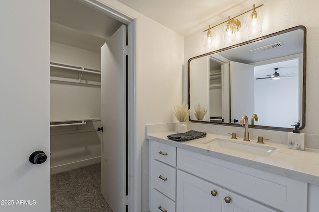 bathroom featuring a walk in closet, visible vents, and vanity