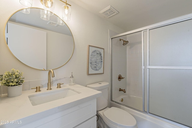 bathroom featuring toilet, visible vents, combined bath / shower with glass door, and vanity