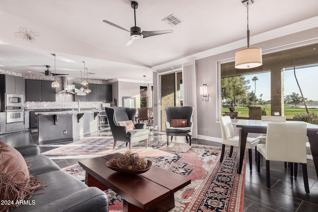 living room with ceiling fan, dark tile patterned floors, lofted ceiling, and ornamental molding