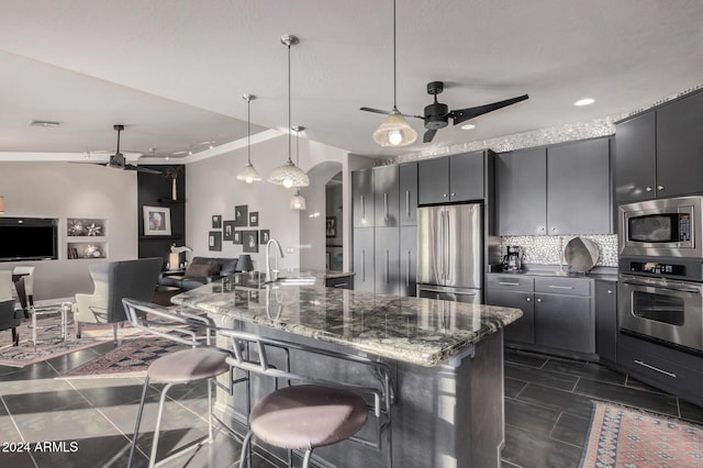 kitchen with a breakfast bar, sink, hanging light fixtures, tasteful backsplash, and stainless steel appliances