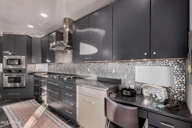 kitchen with stainless steel appliances, dark tile patterned flooring, tasteful backsplash, and wall chimney exhaust hood