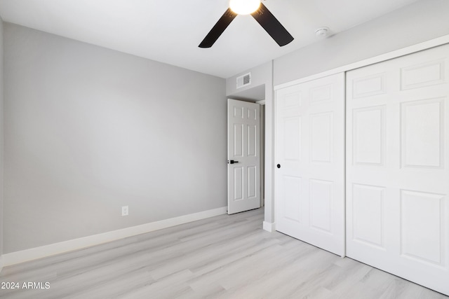 unfurnished bedroom with ceiling fan, light wood-type flooring, and a closet