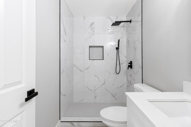 bathroom with a tile shower, vanity, and toilet