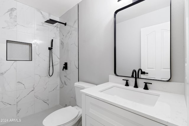 bathroom with tiled shower, vanity, and toilet