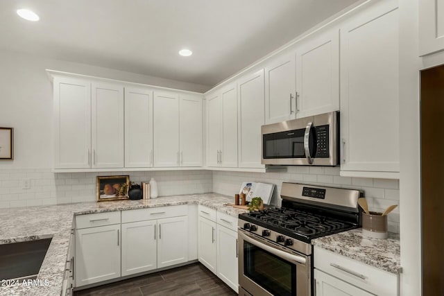 kitchen featuring light stone countertops, backsplash, stainless steel appliances, white cabinets, and dark hardwood / wood-style floors