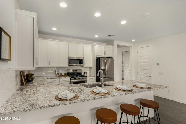 kitchen featuring dark wood-type flooring, white cabinets, sink, tasteful backsplash, and stainless steel appliances