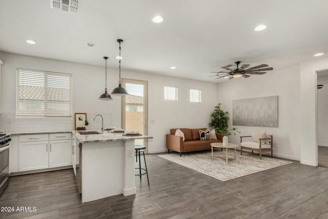 kitchen featuring sink, dark hardwood / wood-style floors, decorative light fixtures, a kitchen bar, and white cabinets