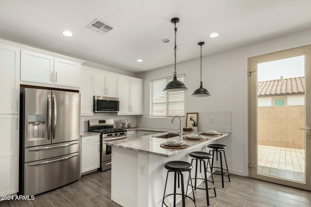 kitchen featuring sink, kitchen peninsula, hardwood / wood-style flooring, white cabinetry, and stainless steel appliances