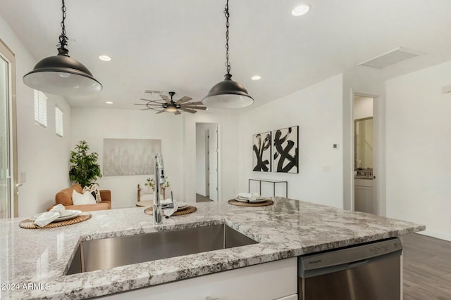 kitchen with light stone countertops, decorative light fixtures, stainless steel dishwasher, and sink