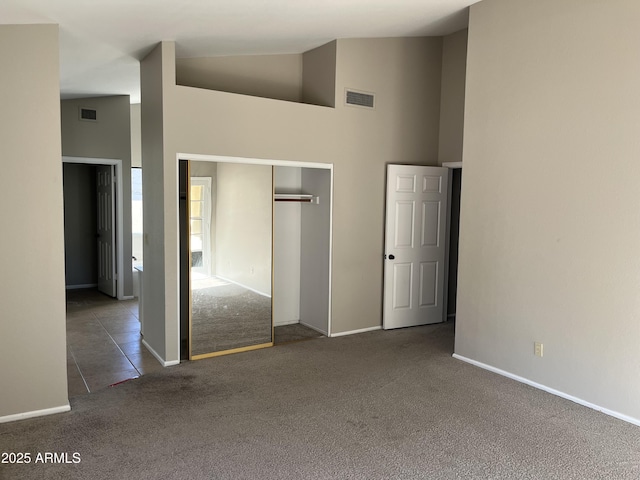 unfurnished bedroom with carpet, a closet, visible vents, high vaulted ceiling, and baseboards