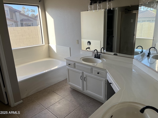 bathroom featuring tile patterned flooring, a garden tub, a sink, and double vanity