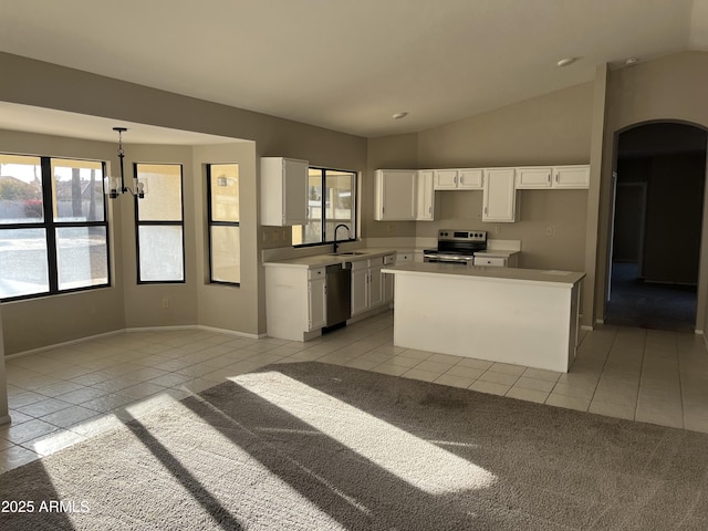 kitchen with light tile patterned floors, lofted ceiling, appliances with stainless steel finishes, white cabinetry, and a sink