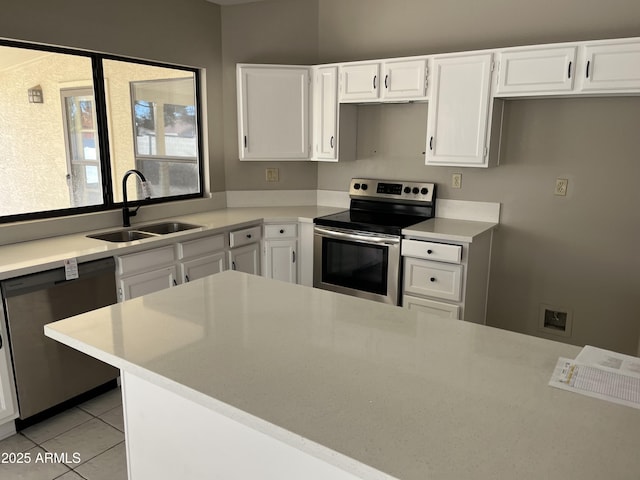 kitchen featuring light countertops, appliances with stainless steel finishes, white cabinets, a sink, and light tile patterned flooring