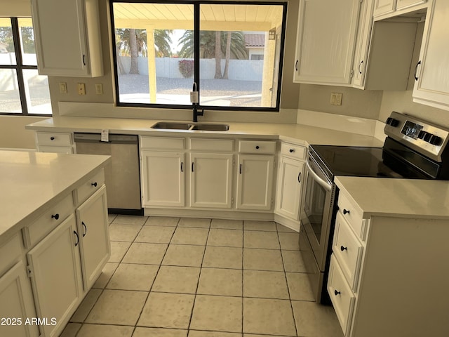 kitchen featuring stainless steel appliances, light countertops, white cabinetry, a sink, and light tile patterned flooring